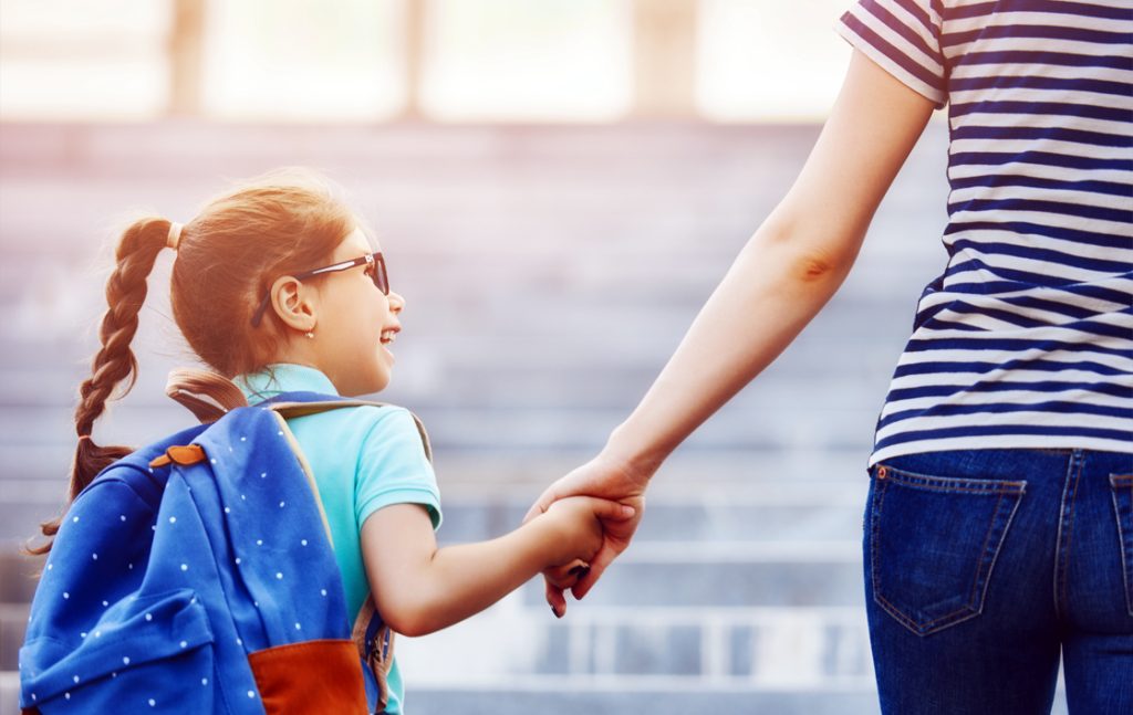 Parent holding their child's hand walking them to school